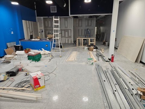 Polished gray retail showroom floor with light reflections and industrial exposed ceilings.