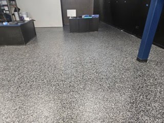 Reflective gray epoxy flooring in a large open room with bright overhead light reflections.
