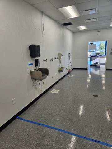 Commercial-grade stainless steel sink and industrial plumbing fixtures installed in a maintenance room.
